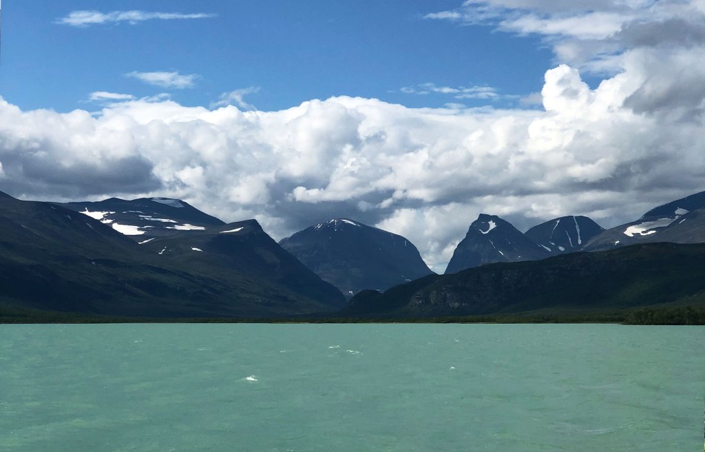 Båtfärd över Láddjujávris turkosa glaciärvatten med Sinnicohkka och Duolbagorni i fonden.