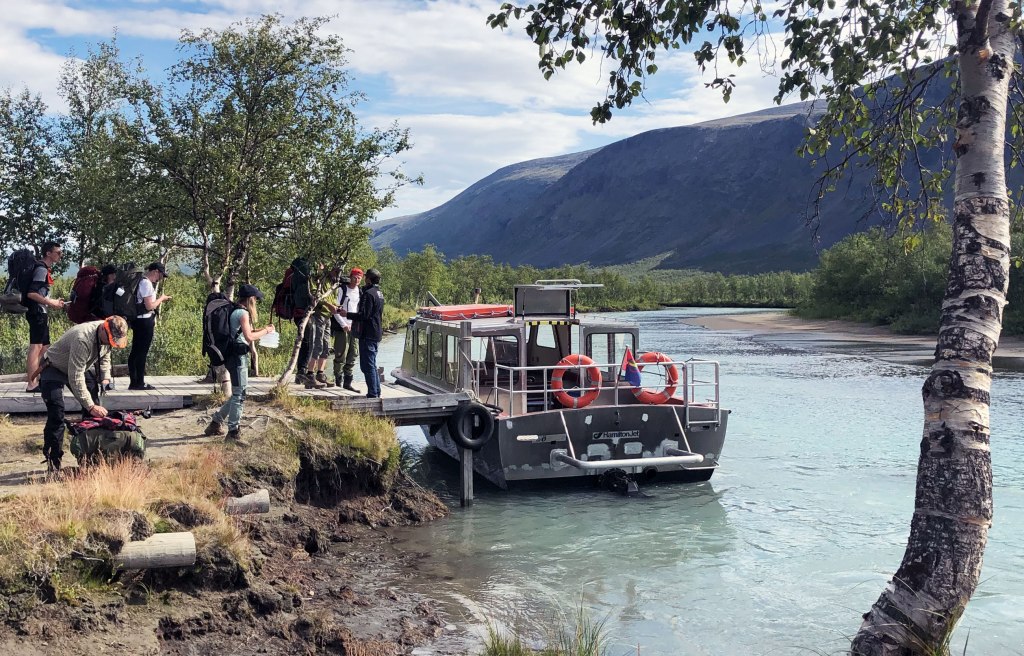 Båtfärd över Láddjujávris turkosa glaciärvatten med Sinnicohkka och Duolbagorni i fonden.